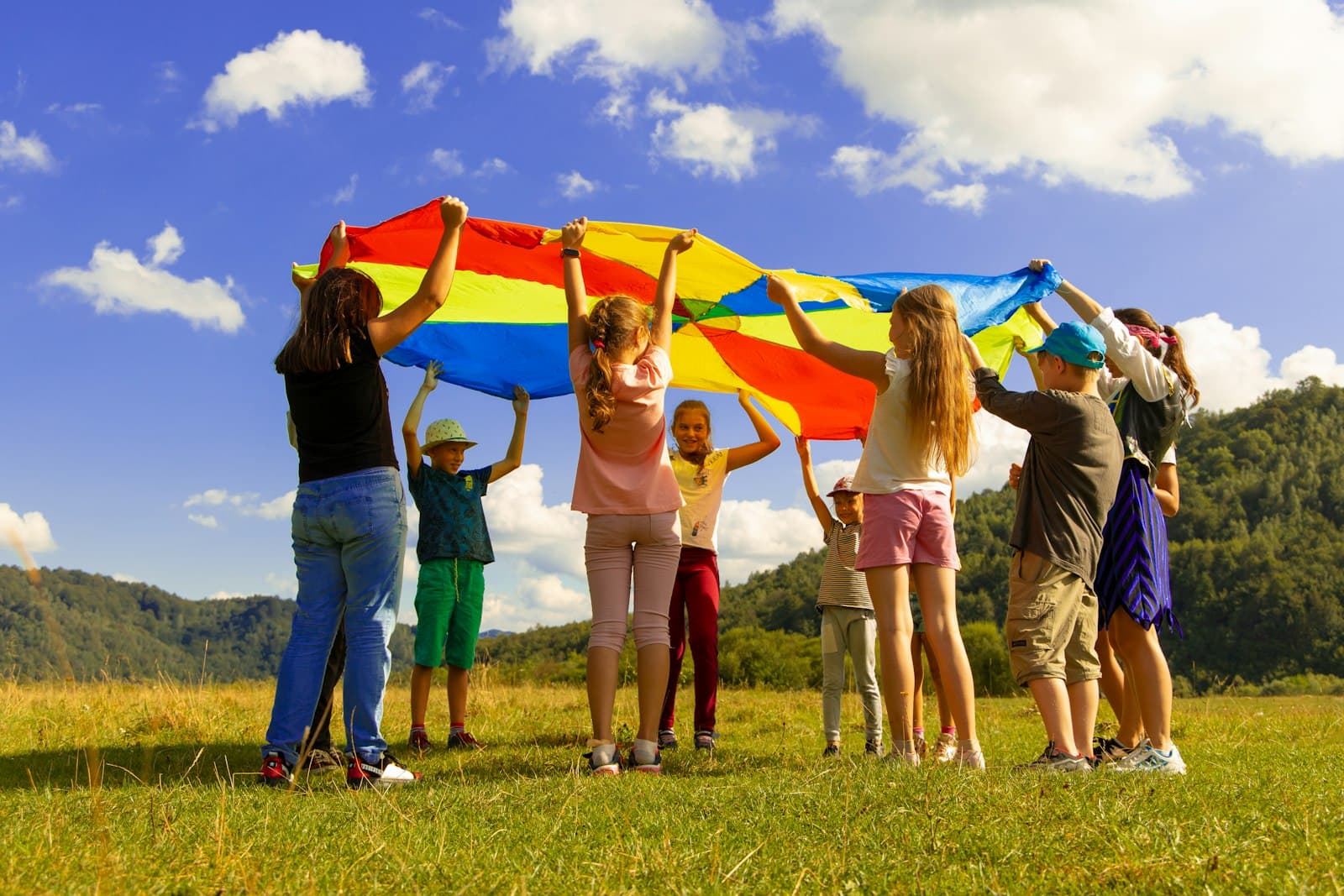 Niños jugando con un paracaídas de colores en el césped